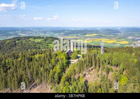 Questa vista aerea cattura la torre di osservazione di Svatobor circondata da foreste lussureggianti e colline ondulate in Cechia in una giornata limpida. I visitatori possono ammirare paesaggi mozzafiato da questo punto panoramico. Foto Stock