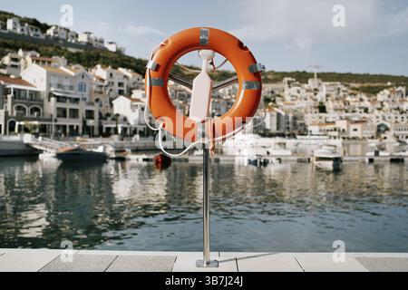 Lifebuoy su uno stand con un fermo si trova su un molo a Lustica Bay. Montenegro. Foto Stock