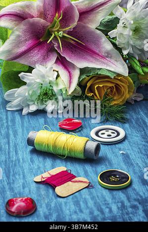 Accessori per cucire con bouquet di fiori freschi su sfondo turchese Foto Stock