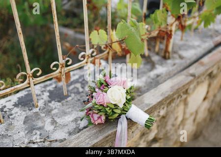 Bouquet nuziale di rose bianche e rosa, rami di bosso, aronia, fiori di veronica, nastri rosa e bianchi sullo schermidore in mattoni. Foto Stock