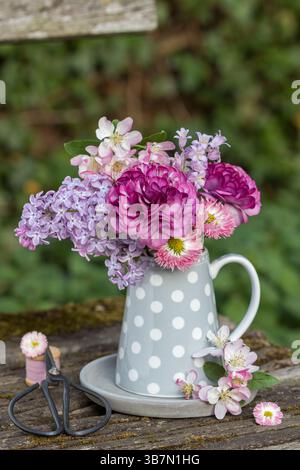 bouquet di ranunculus rosa, lilla, bellis, campanelli e fiori di granchio in lattina di latte Foto Stock