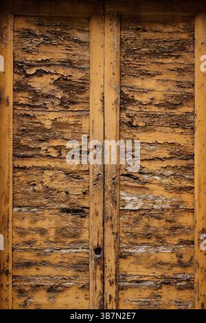 Un vecchio ingresso in legno sbucciato a due canne con un pomello in metallo. Foto Stock