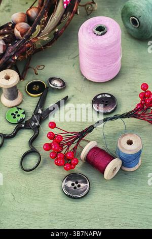 Filetto per cucire, bottoni e decorazioni su fondo in legno Foto Stock