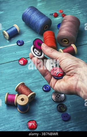 Sarta a mano con bottoni di legno su sfondo turchese Foto Stock