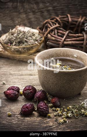 Vecchia tazza di ferro di tè e bacche secche della rosa selvatica su un tavolo di legno Foto Stock