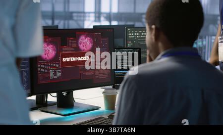 Gli ingegneri vedono un popup di violazione del sistema sullo schermo del PC nel data center, chiedendo aiuto al team di sicurezza informatica. Server farm worker che vede incidenti di sicurezza che interessano il sistema di rete, videocamera A. Foto Stock