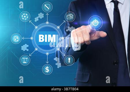 Modellazione delle informazioni di costruzione. Uomo che utilizza lo schermo virtuale con l'abbreviazione BIM e diverse icone, primo piano Foto Stock