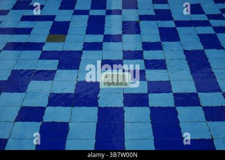 La griglia di drenaggio dell'acqua è posizionata sul fondo della piscina tra piastrelle blu. Foto Stock