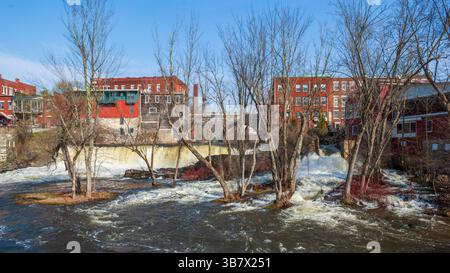 Cascate di Middlebury sull'Otter Creek con edifici storici e un ponte in pietra sopra, alte acque sorgive a Middlebury, Vermont, Stati Uniti. Foto Stock