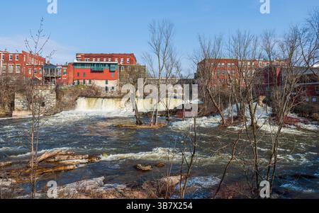 Cascate di Middlebury sull'Otter Creek con edifici storici e un ponte in pietra sopra, alte acque sorgive a Middlebury, Vermont, Stati Uniti. Foto Stock