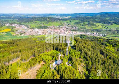 La vista aerea da un drone cattura la torre di osservazione di Svatobor, situata tra la vegetazione lussureggiante, fornendo una splendida prospettiva della città di Susice, annidata nella valle sottostante. Foto Stock