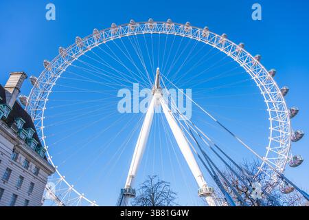 Il London Eye domina maestosamente la città, mostrando la sua imponente struttura. I cieli azzurri offrono uno sfondo mozzafiato, enfatizzando la bellezza architettonica e la grandiosità. Foto Stock