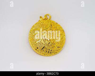 La composizione presenta un luminoso ciondolo in oro, meticolosamente realizzato con intricati dettagli floreali in filigrana, che si abbina a un design pulito e neutro Foto Stock