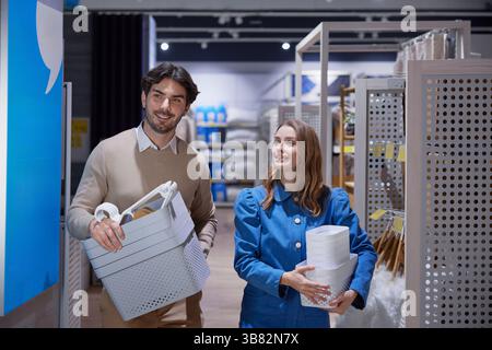 La coppia ama fare shopping insieme, portando con sé i suoi articoli colorati in un negozio vivace e moderno Foto Stock