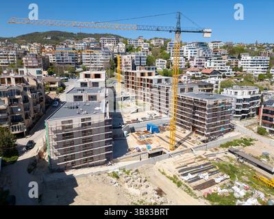 Edifici residenziali moderni in costruzione con ponteggi e gru, catturati in una giornata di sole Foto Stock