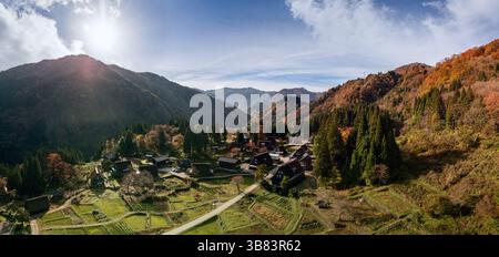 Panoramic drone view of Ainokura village in Toyama, Japan with vivid autumn colors, traditional gassho houses and forested mountain landscape under br Foto Stock