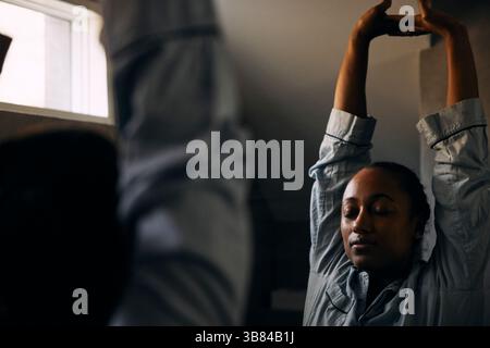 Riflesso di donna che si allunga con gli occhi chiusi mentre si trova davanti allo specchio in bagno Foto Stock