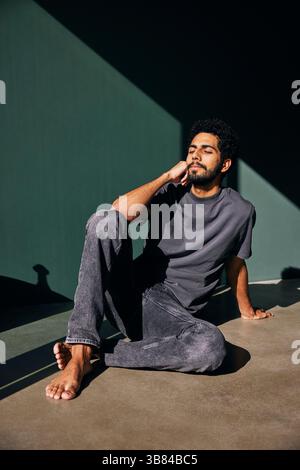 Uomo appoggiato al gomito con gli occhi chiusi seduto sul pavimento di casa Foto Stock