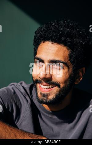 La luce del sole splende su un uomo barbuto felice che guarda lontano Foto Stock
