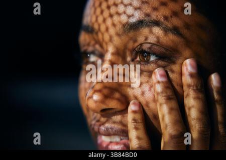 Primo piano della luce del sole che splende sulla donna toccando la guancia con la mano Foto Stock