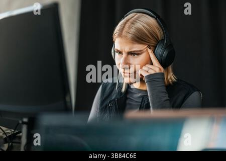 Programmatore di computer femminile che indossa cuffie wireless utilizzando il computer in ufficio Foto Stock