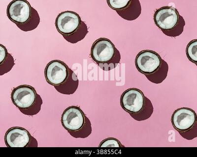 Layout creativo delle noci di cocco metà su sfondo rosa. Modello tropicale, vista dall'alto o disposizione piatta. Pop art hard light con sfondo estivo minimalista Foto Stock