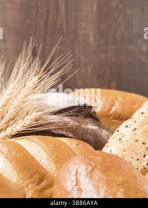 Vista ravvicinata del pane diverso su sfondo marrone in legno. Copia spazio. DOF poco profondo. Verticale Foto Stock