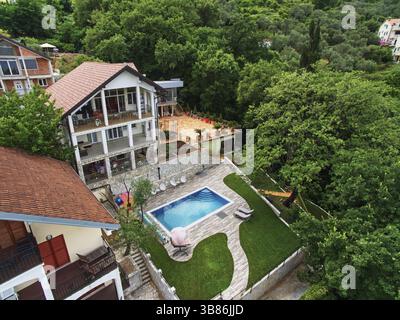 Piscina su un prato verde vicino ad una villa a tre piani. Drone., comune di Kotor, Montenegro, Europa Foto Stock