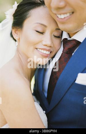 La sposa abbraccia lo sposo, appoggiando la testa sulla spalla. Verticale. Foto Stock