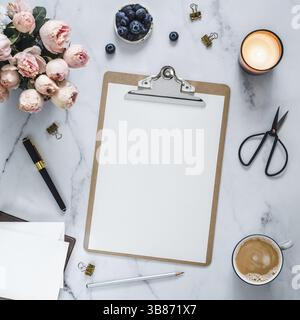 Vista dall'alto degli Appunti con pagina vuota bianca. Appunti, fiori, candela profumata su marmo bianco. Il femminile ufficio domestico si può foggiare con un foglio di pape vuoto Foto Stock