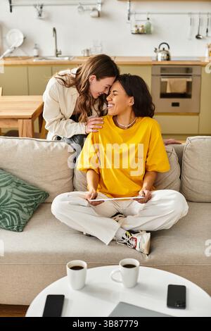 Due donne condividono un momento di gioia, creando un'atmosfera calda a casa piena di amore. Foto Stock