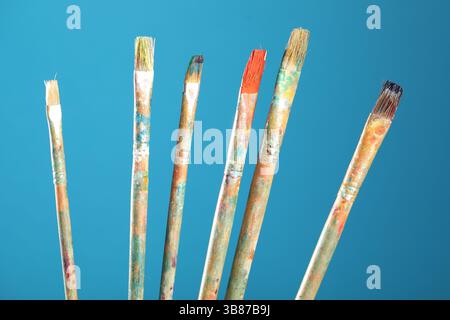Pennelli sporchi su sfondo azzurro, primo piano Foto Stock