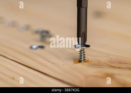 vite per il fissaggio di assi di legno intrecciati in una tavola di pino, primo piano Foto Stock