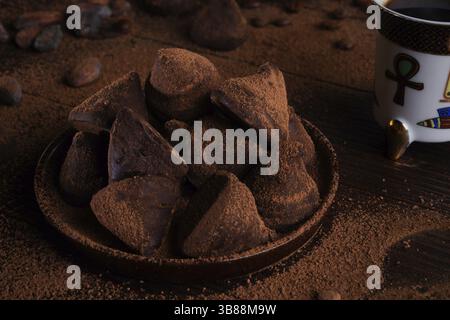 Deliziosi e salutari tartufi di cioccolato intorno agli ingridienti con fagioli di cacao naturali, polvere, burro di cacao, zucchero di canna e tazza di caffè. dolci sani c Foto Stock