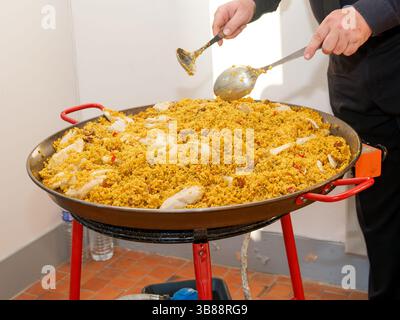 Grande cottura della paella in una padella tradizionale per un evento all'aperto o un servizio di catering festivo. Foto Stock