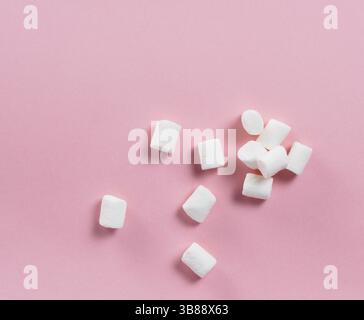 Marshmallows su sfondo rosa con copyspace. Appartamento laici o vista dall'alto. Lo sfondo o la texture di coloratissimi mini marshmallows. Inverno sfondo alimentare conc Foto Stock