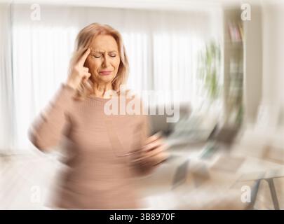 Donna che soffre di mal di testa e sta in salotto Foto Stock