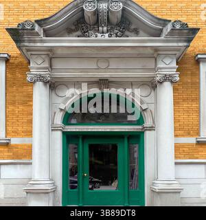 Grande entrata neoclassica con frontone ornato, colonne corinzie e una porta ad arco verde adagiata su una facciata in mattoni gialli a Chicago Foto Stock