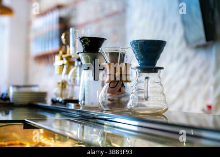 Foto di mezzogiorno all'interno di un bar di Cartagena, Colombia, che mostra l'elegante attrezzatura manuale per la preparazione del caffè su un banco di vetro con uno sfondo accogliente. Foto Stock
