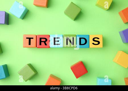 Word Trends in cubi di legno con lettere su sfondo verde chiaro, vista dall'alto Foto Stock