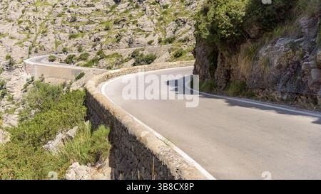 Stretta strada tortuosa con barriere in pietra che si snodano attraverso i monti Tramuntana a Maiorca. Isole Baleari, Spagna Foto Stock