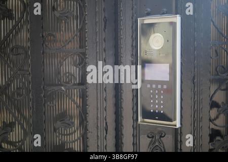 Moderno sistema interfono montato su un cancello nero decorato Foto Stock