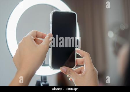 Mani di influencer che regolano lo smartphone sul ring a casa. Influencer e persona con pacchetto, registra video su social media e contenuti creativi Foto Stock
