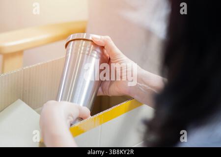 Immagine ravvicinata di una donna che riceve un bicchiere in acciaio inossidabile dopo aver aperto una cassetta postale a casa per la consegna e lo shopping online. Foto Stock