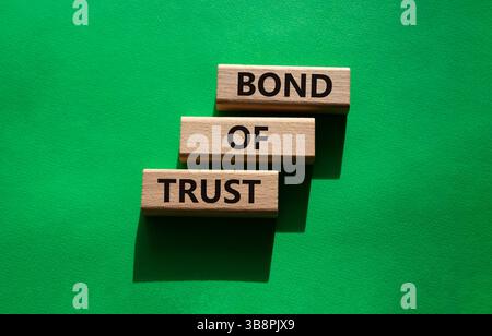 Simbolo del legame di fiducia. Blocchi di legno con parole Bond of Trust. Bellissimo sfondo verde. Business e Bond of Trust. Copia spazio. Foto Stock