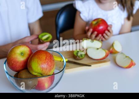 Primo piano di mani che affettano mele fresche su una tavola di legno per uno spuntino sano Foto Stock