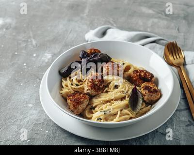 Polpette di parmigiano con pasta Carbonara in piatto bianco su fondo grigio. Primo piano vista della carbonara cremosa con spazio copia a sinistra Foto Stock
