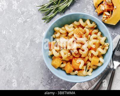 Fusilli con zucca, rosmarino e formaggio brie. Idea ricetta pasta. Cibo vegetariano. Pasta fatta in casa piatto in vaso blu su cemento grigio backgrou Foto Stock