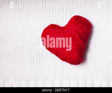 Cuore di filo rosso su tessuto bianco lavorato a maglia. San Valentino sfondo Foto Stock