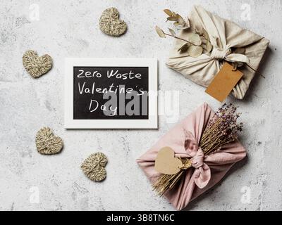 Concetto di San Valentino Zero Waste. Panno eco-compatibile in stile Furoshiki e lavagna con lettere Zero Waste San Valentino in grigio Foto Stock